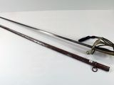 une vieille épée et d'autres objets posés sur une surface blanche
