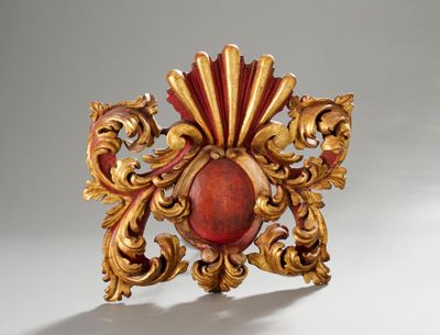 une broche rouge et dorée sur un fond blanc