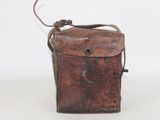an old brown leather bag with a metal handle on a white surface