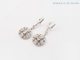 une paire de boucles d'oreilles ornées de diamants, posées sur un fond blanc