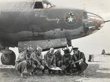 a group of men sitting in front of an old airplane