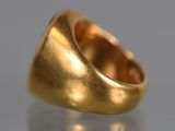 a close up of a gold ring on a reflective surface