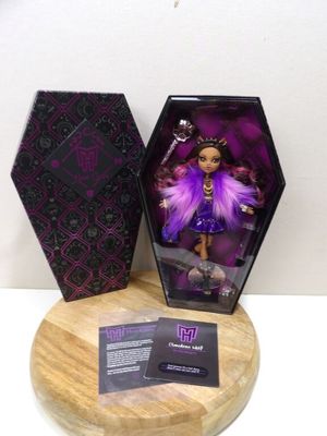 l'image d'une poupée vêtue d'une robe violette et aux cheveux violets, dans une boîte noire