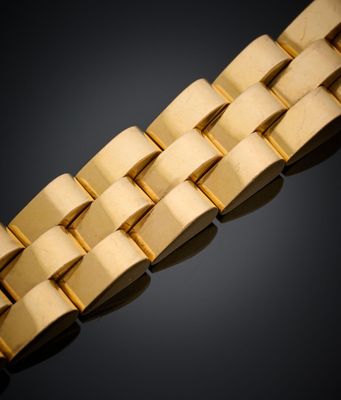 gros plan d'un bracelet en or sur une surface noire