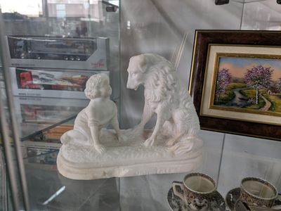 une statue représentant un chien et un enfant, exposée dans une vitrine