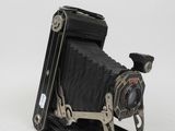 an old black camera sitting on top of a white surface
