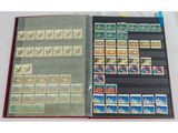un livre ouvert, sur lequel sont posés des timbres, posé sur une table