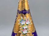 a blue and gold vase with a gold top on a stand