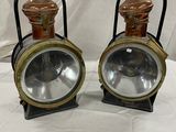 une paire de lampes de chemin de fer anciennes, posées sur des supports, sur un tissu blanc