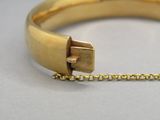un gros plan d'un bracelet en or muni d'un fermoir sur une chaîne