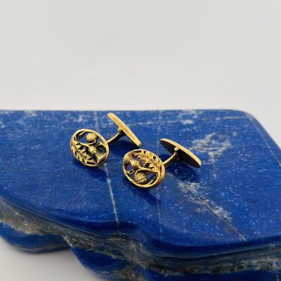 a close up of a pair of gold earrings on a blue stone