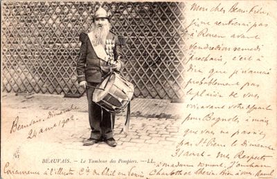 une vieille photo représentant un homme avec un tambour devant une clôture
