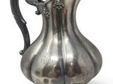 a silver pitcher that is sitting on a stand