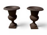 pair of cast iron urns on pedestals on a white background