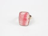 gros plan d'une bague en pierre rose sur une surface blanche