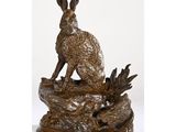 une statue en bronze représentant un lapin assis sur un rocher