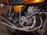 a yellow motorcycle parked in a garage with a brick wall in the background