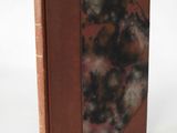 an old book with a brown cover sitting on top of a white table