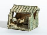 une petite figurine représentant une crèche avec un chien à l'intérieur
