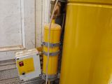 a yellow tank with a hose attached to it next to a window