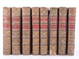 several old books are lined up in a row on a white surface