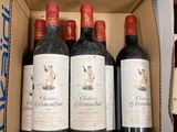 six bottles of red wine in a cardboard box on a table