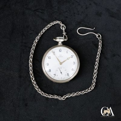 une montre de poche en argent attachée à une chaîne, posée sur une surface noire