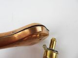 a small brass object on a white surface next to a small brass object