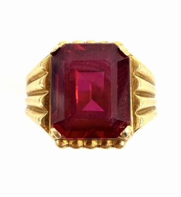 a close up of a ring with a red stone in it