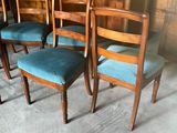four wooden chairs with blue upholstered cushions sit in a room