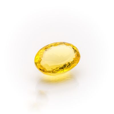a yellow sapphire stone on a white surface
