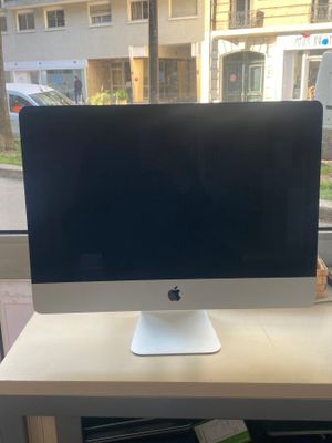 un ordinateur de bureau Apple posé sur un bureau près d'une fenêtre