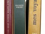 trois livres sont empilés sur une surface blanche