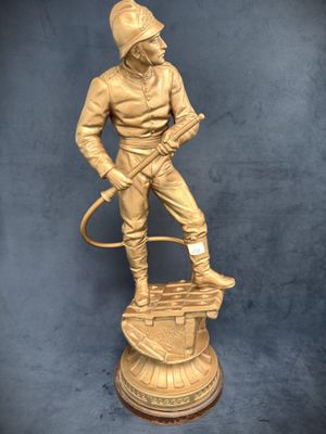 gold statue of a man with a hose on top of a pedestal