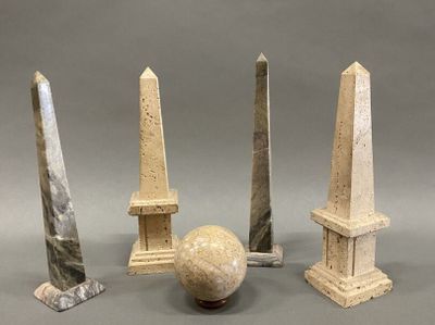 three stone obelisk and a marble ball on a gray surface