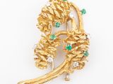 a close up of a gold brooch with green and white stones