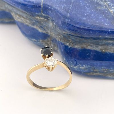 an image of a gold ring with two black and white diamonds