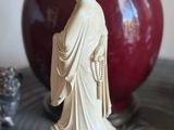 a statue of a woman standing on a table next to a vase