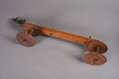 un jouet en bois à l'ancienne, muni de roues, posé sur une surface grise