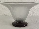 a glass vase with a black base on a table