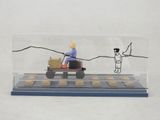 figurine représentant un homme au volant d'un tracteur miniature, avec un panier de biscuits à l'arrière