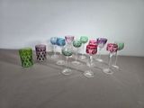 Plusieurs verres à vin de différentes couleurs sont alignés sur une table