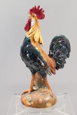 une figurine représentant un coq posée sur un socle transparent