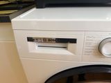 a white washer sitting on top of a washer in a kitchen
