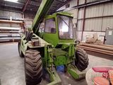a large green tractor parked inside of a building