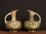 two vases sitting on a table with a black background
