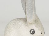 a small white rabbit figurine sitting on a white surface