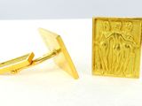 two gold cufflinks with a picture of a man and a woman on them