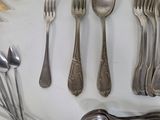 many different types of spoons and forks laid out on a table