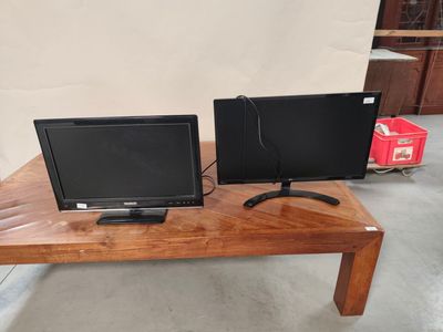 two monitors sitting on a wooden table with a phone on it